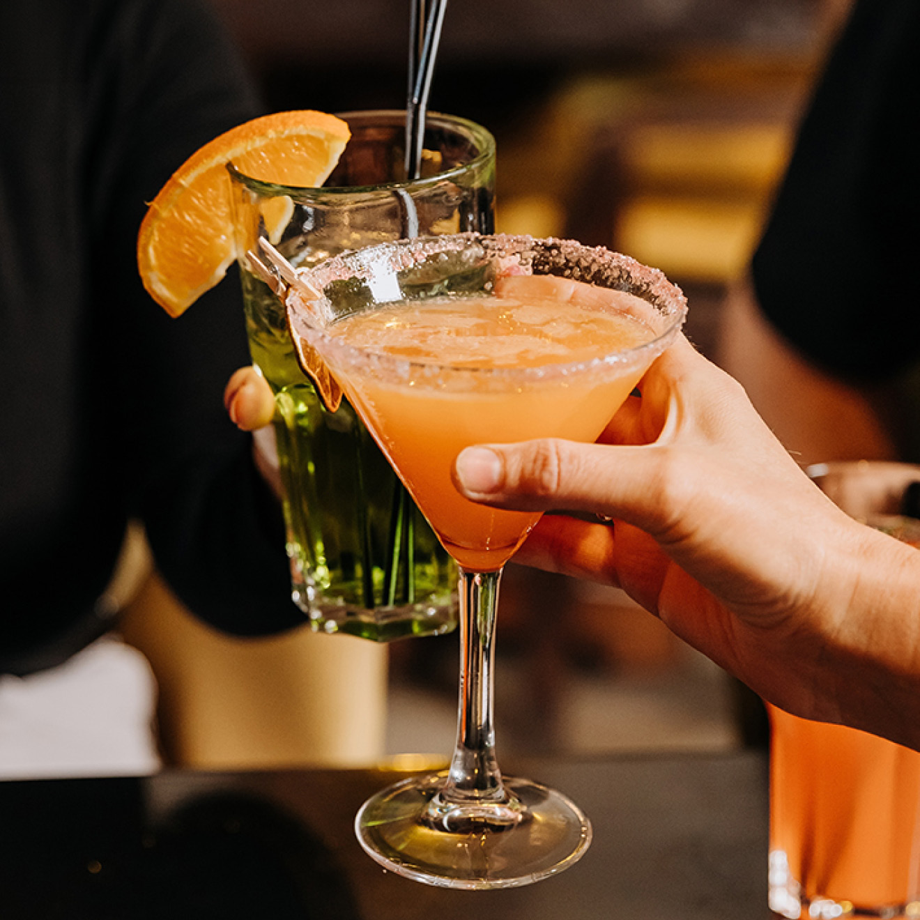 Two individuals raising their drinks in a toast, celebrating a special moment together.
