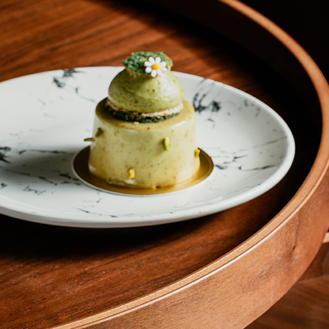 A small dessert elegantly presented on a white plate, resting on a wooden table.